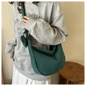Detail of dark green corduroy dumpling bag featuring ribbed texture and matching round pouch