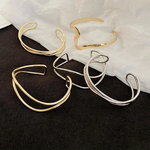 Macro shot of minimalist wave and geometric crossover gold and silver bangles set
