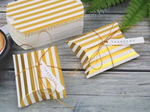 Flat lay of gold striped pillow boxes with Thank You tags on a wooden background