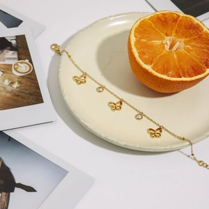 Detailed shot of 18K gold plated butterfly bracelet with zircons on a ceramic plate