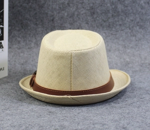Close-up of a beige straw fedora hat featuring a brown leather band and fine weaving