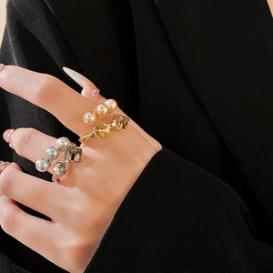 Detail of luxury zircon pearl open rings worn on hand against black fabric background