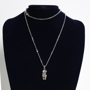 Detailed view of silver astronaut pendant necklace with 'HUG ME' engraving on black bust