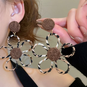 Gros plan détaillé sur des boucles d'oreilles fleurs en tissu léopard et clous dorés