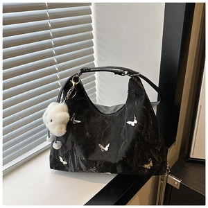 Detail of black nylon bag with silver metal butterfly and white plush cloud charm