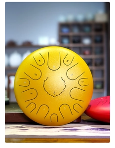 Detailed view of a yellow steel tongue drum with numbered scales and metal texture