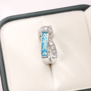 Detail view of silver crossover ring with square aquamarine stones and tiny diamonds