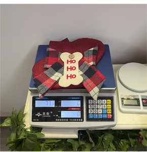 Macro detail of red plaid dog scarf with white bone decor and HO HO HO embroidery