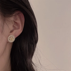 Close-up of elegant gold flower earring featuring micro pearls and sparkling zircon stones