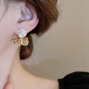Close-up of a model wearing gold pleated flower earrings with white pearl accents
