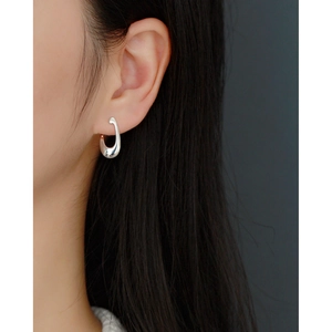 Close-up of a minimalist irregular silver hoop earring worn on a model's ear