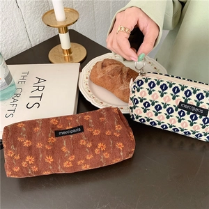 Detail of vintage corduroy floral pencil cases and tulip pouches on a cozy wooden desk