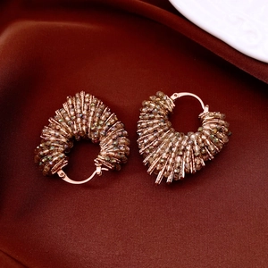 Détail de boucles d'oreilles cœur perlées de cristaux champagne sur soie