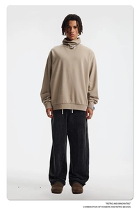 Scatto in studio a figura intera con felpa beige a collo alto e pantaloni grigi