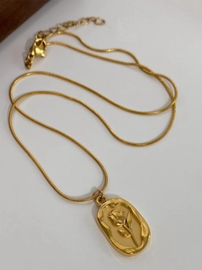 Detail of gold snake chain necklace featuring a relief tulip pendant and lobster clasp