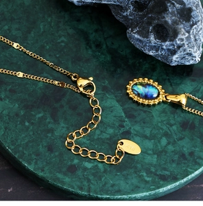 Detailed macro view of 18K gold-plated oval abalone shell pendant and K18 hallmark tag