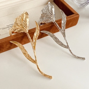 Close-up of tulip-shaped metal brooches in gold and silver with elegant pleated texture
