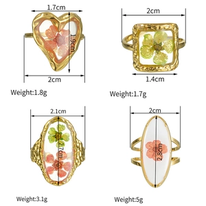 Detail view of four gold resin rings with dried flowers in various geometric shapes