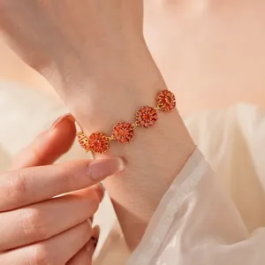 Close-up of gold plated flower bracelet with orange marquise zircons on a model's wrist