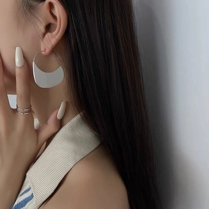 Orecchini geometrici minimalisti in argento indossati da una modella di profilo