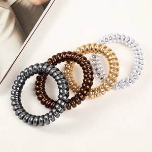 Close-up of four metallic spiral hair ties in grey, brown, gold, and silver shades