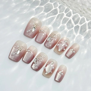 Pink cat eye press-on nails with 3D pearls, rhinestones, and butterfly patterns