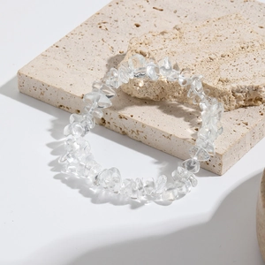 Detail showing natural clear quartz chip stone bracelet on a textured stone background