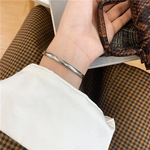 Close-up of minimalist silver polished open bangle worn on a female wrist with chic outfit