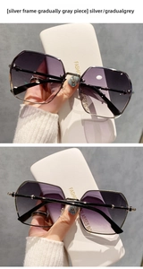 Detail view of silver rimless hexagonal sunglasses with gradual grey lenses and white case