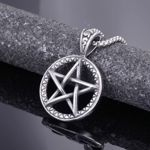 Macro view of silver stainless steel pentagram pendant on a dark stone texture