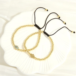 Detail of adjustable gold beaded bracelets with blue rhinestone Hamsa hand charms