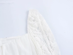 Close-up detail of white lace shoulder and bell sleeve texture on a mini dress