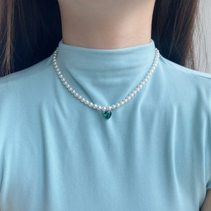 Elegant pearl necklace with green heart zircon pendant shown on a model neck