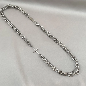 Close-up of double-layered silver chain necklace with small diamond-set cross pendant
