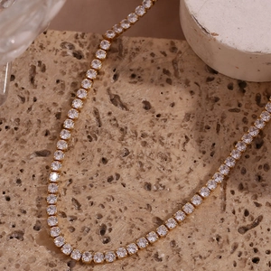Close-up of 14K gold plated tennis necklace with cubic zirconia on beige stone
