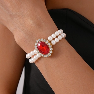 Detail view of a vintage double-row faux pearl bracelet with a large red oval gemstone