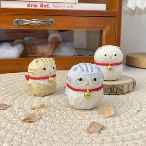 Detailed view of hand-carved wooden round cat figurines with bell and matte finish