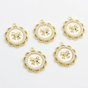 Detailed view of 5 golden round pendant charms with bow tie motif and pearl border