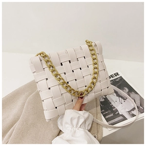 Detail view of woven white handbag featuring gold chain handle and detachable strap