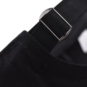 Close-up of adjustable metal buckle on black cotton baseball cap with neat stitching