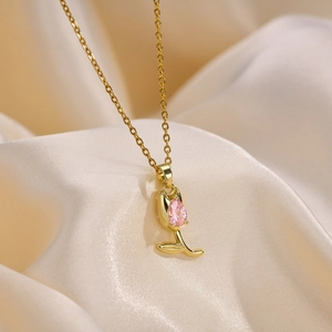 Detail of golden tulip necklace with a pink pear-shaped zircon on champagne silk fabric