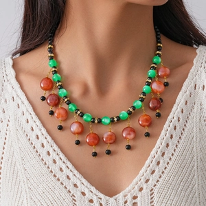 Detailed view of bohemian clavicle necklace with green beads and red resin tassels