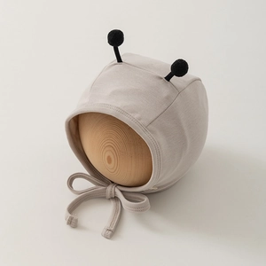 Detail of baby bee earflap hat in ribbed knit fabric with cute black pom-pom antennae