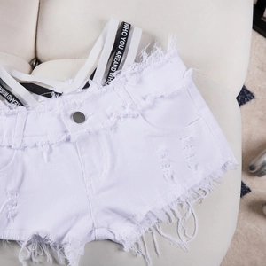 Dettaglio di shorts in denim bianco con bordi sfilacciati e fettuccia con scritte nere