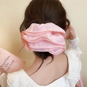 Détail d'un chouchou rose en dentelle multicouche porté par un modèle de dos