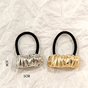 Close-up of gold and silver hollow metal ponytail holders with irregular vertical texture