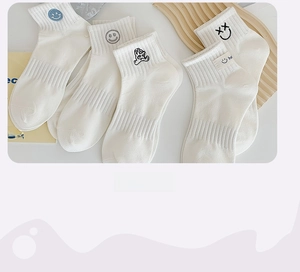 Close-up of white cotton ankle socks featuring cute cartoon embroidery and ribbed texture