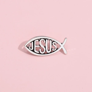 Minimalist silver fish-shaped Jesus brooch with hollow metal lettering on pink backdrop