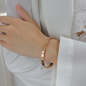 Close-up of rose gold heart-inlaid titanium steel bracelet worn with elegant outfit