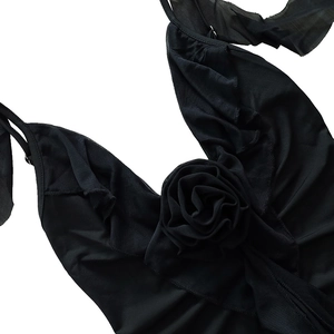 Détail d'une robe noire sexy à col en V avec rose 3D et tissu plissé élégant